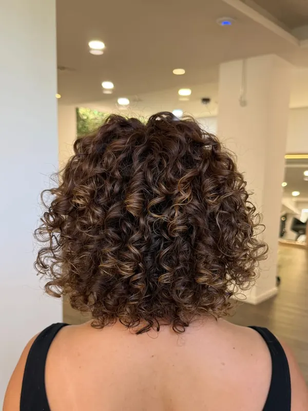 O mesmo cabelo com cachos definidos e volume, depois do atendimento