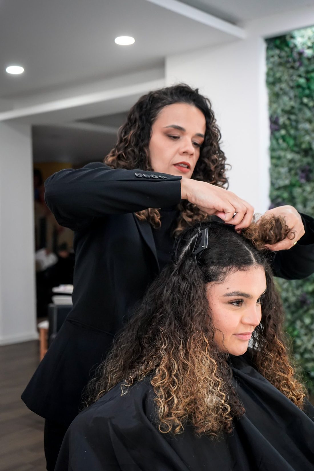 Vivian Oliveira separando mechas do cabelo cacheado de uma cliente na Curly Concept